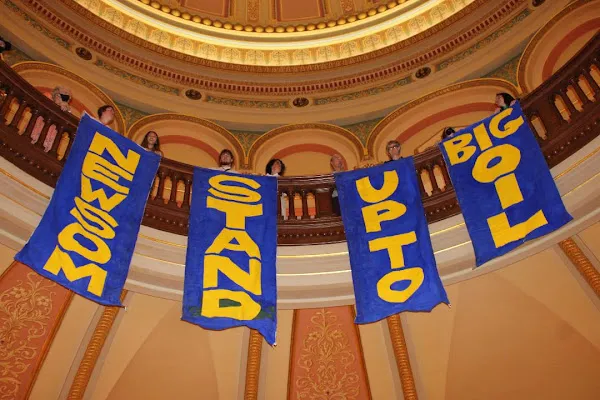 Activists unfurl banners calling on Newson to stand up to Big Oil, stop oil drilling expansion